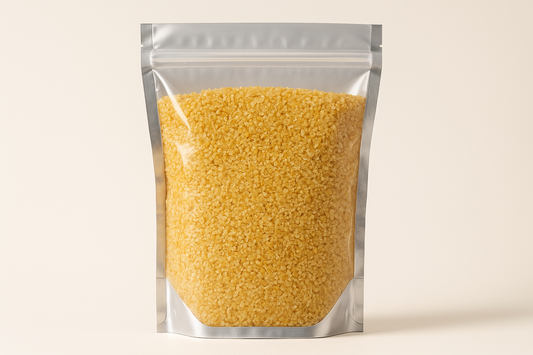 A highly realistic, front-facing product photo of a 1kg stand-up pouch made of aluminum with a fully transparent front from top to bottom, clearly showing the contents inside. The contents should be split wheat bulgur, packed naturally with realistic textures and lighting. The aluminum is only visible on the sides and a small portion at the bottom. The image should have soft, natural shadows and plain background (hex #faf6f1). No text, labels, or branding just the pouch and its contents.